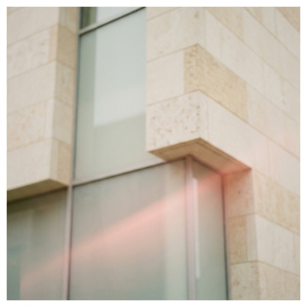 Détail d'une façade contemporaine, ton crème et reflet rosé